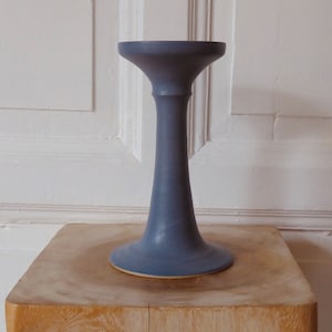 Könnte beinhalten: Ein blauer Kerzenhalter aus Keramik mit einem breiten Sockel und einem hohen, schlanken Stiel.