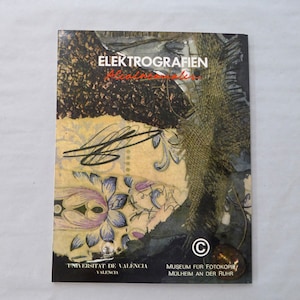 Può includere: Una copertina di libro con un collage di carta e tessuto testurizzati. Il titolo "Elektrografien" è stampato in lettere rosse. Il libro è dell'Universitat de Valencia e del Museum fur Fotokopie, Mulheim an der Ruhr.