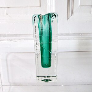 May include: A clear glass vase with a rectangular shape and a vibrant teal interior. The vase has a textured, slightly irregular surface, giving it a unique, handcrafted appearance. The teal interior is visible through the clear glass.