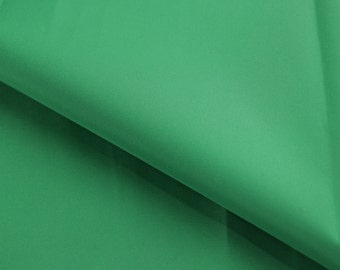 May include: A close-up of a smooth, solid green fabric. The fabric is folded in half, showing the texture and color.