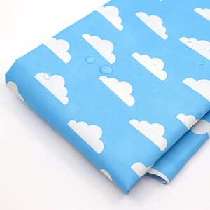 May include: A close-up of a light blue fabric with a white cloud pattern. The fabric is waterproof and has water droplets on it.