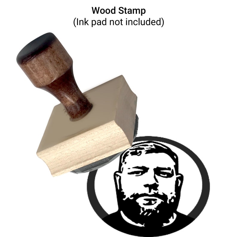 Puede incluir: Un sello de madera con una imagen en blanco y negro de un hombre con barba. El sello se est&aacute; utilizando para crear una impresi&oacute;n de la imagen en una superficie blanca. El texto "Wood Stamp (Ink pad not included)" es visible sobre el sello.