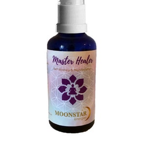 May include: A dark blue glass bottle with a white spray nozzle. The label reads "Master Healer" with the text "Self Mastery & Manifestation" and a purple lotus flower design. The brand name "MOONSTAR energies" is also visible.