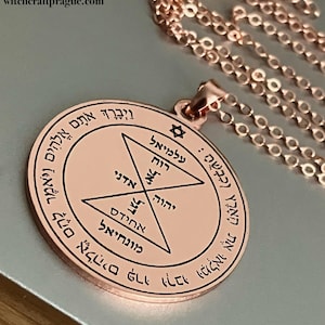 May include: A rose gold pendant necklace with a circular charm featuring a star of David and Hebrew text. The charm is inscribed with the words "לִבְנִי עֲבָדִי" and "אֵשׁ הַשָּׁמַיִם".