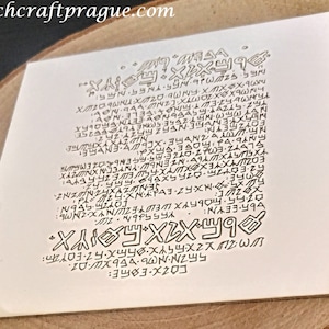 May include: A white card with a black and white design of a symbol with text. The text includes the website "witchcraftprague.com".
