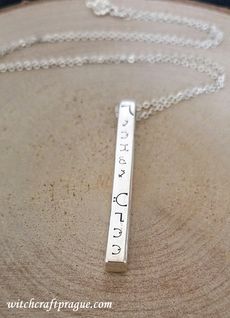 May include: Silver bar necklace with engraved astrological symbols. The symbols include the sun, moon, Mercury, Venus, Mars, Jupiter, Saturn, Uranus, Neptune, and Pluto.