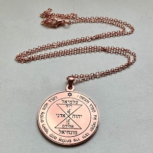 Può includere: Una collana con pendente color rame. Il pendente rotondo presenta testo ebraico e disegni geometrici. La catena della collana è anch'essa color rame. Il pendente ha una stella in cima e un anello per la catena.