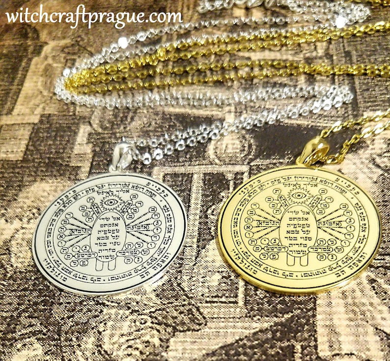 May include: Two circular pendants with intricate designs and text. One is silver-toned, the other gold-toned, both hanging on delicate chains. The pendants feature detailed symbols and inscriptions, likely for spiritual or symbolic purposes.
