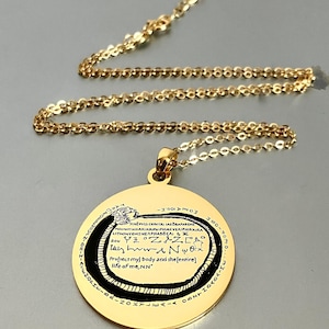 May include: Gold-colored necklace with a circular pendant. The pendant features a black snake design encircling text in a stylized font. The chain and pendant are made of a shiny, reflective metal.