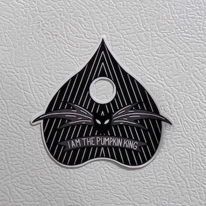 May include: Black and white sticker with a heart shape and a striped pattern. The sticker features a black silhouette of a creature with wings and the text "I AM THE PUMPKIN KING".