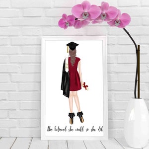 May include: A white framed print with a black and red illustration of a graduate in a cap and gown holding a diploma. The text "She believed she could so she did" is at the bottom of the print.