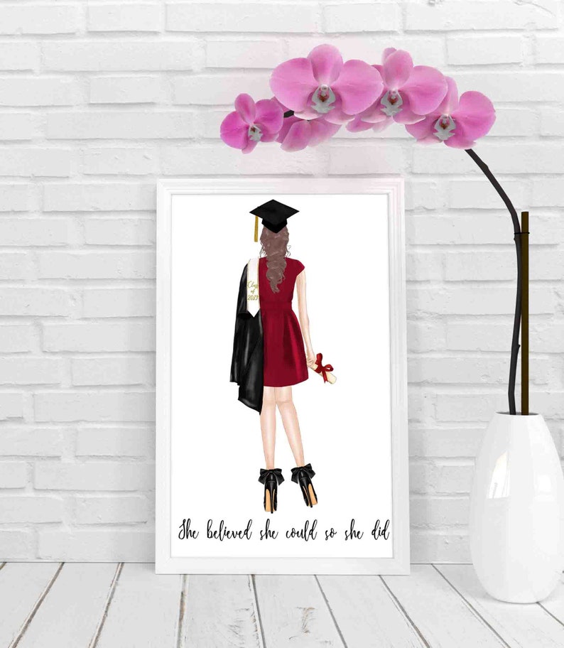 May include: A white framed print with a black and red illustration of a graduate in a cap and gown holding a diploma. The text "She believed she could so she did" is at the bottom of the print.