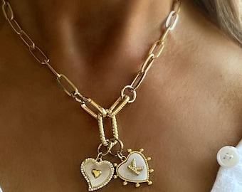 May include: A gold chain necklace with two heart-shaped pendants. One pendant features a small heart design and the other has a bird design.