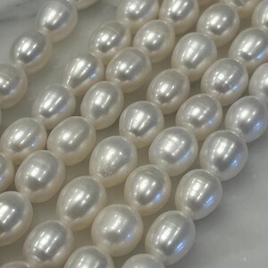May include: A strand of white pearl beads, arranged in rows, showcasing their smooth, lustrous surface.