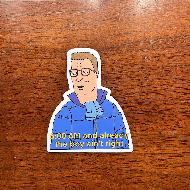 May include: A sticker featuring a cartoon character with a blue jacket and a scarf, with the text "6:00 AM and already the boy ain't right".