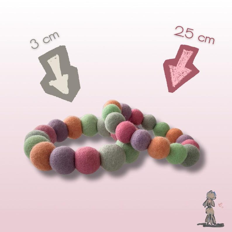 May include: Two felt ball garlands in shades of green, orange, pink, and purple. One garland is 3 cm in diameter, the other is 2.5 cm. The garlands are arranged on a pink background.
