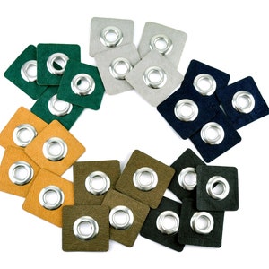 Könnte beinhalten: Sortiment aus bunten quadratischen Stoff-Patches mit Metallösen. Die Patches sind in den Farben Grün, Blau, Braun und Grau.