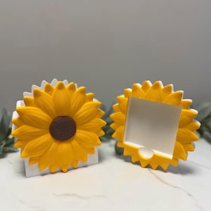 Puede incluir: Dos organizadores de escritorio con forma de girasol. Los organizadores presentan un diseño de girasol amarillo brillante con un centro marrón y una base blanca. Los pétalos de girasol son detallados y el diseño general es alegre y decorativo.