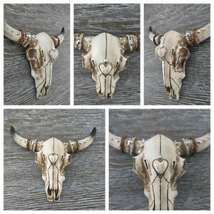 May include: Five white ceramic bull skulls with silver and brown accents. Each skull has a small heart-shaped design in the center of the forehead.