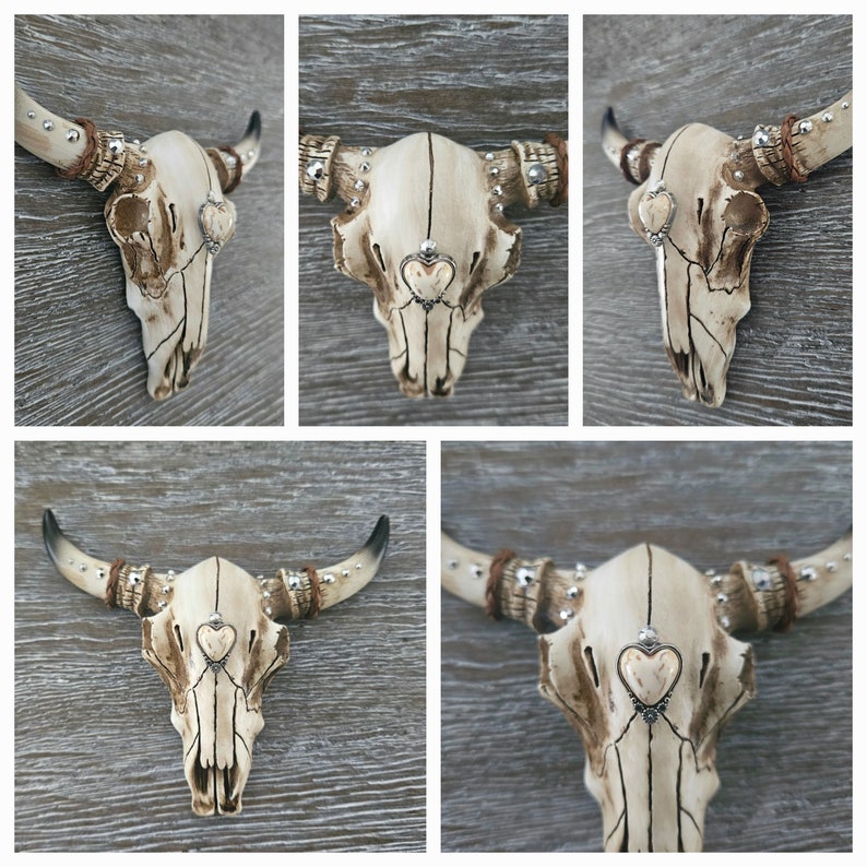 May include: Five white ceramic bull skulls with silver and brown accents. Each skull has a small heart-shaped design in the center of the forehead.