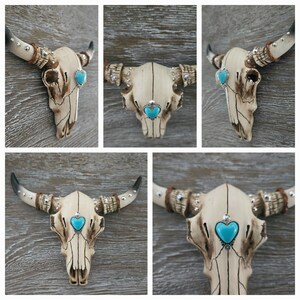 May include: A white ceramic bull skull with turquoise heart-shaped accents. The skull is decorated with silver studs and has a distressed finish.