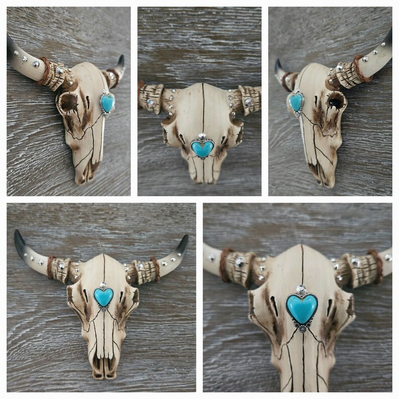 May include: A white ceramic bull skull with turquoise heart-shaped accents. The skull is decorated with silver studs and has a distressed finish.