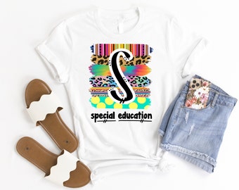 May include: White t-shirt featuring a large black letter "S" with colorful brushstroke designs and the words "special education" in black. The design includes leopard print, stripes, and polka dots. The shirt is paired with denim shorts and white sandals.
