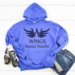 May include: A periwinkle blue hoodie with the text "WINGS Dance Studio" and a wing logo. The hoodie is paired with a pair of blue jeans and black canvas sneakers with white laces.