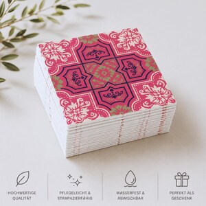May include: A stack of square coasters featuring a vibrant pink, dark blue, and light green floral tile pattern. The bottom of the image displays four icons with the German text: HOCHWERTIGE QUALIT&Auml;T, PFLEGELEICHT & STRAPAZIERF&Auml;HIG, WASSERFEST & ABWISCHBAR, and PERFEKT ALS GESCHENK.