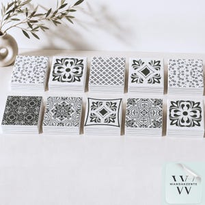 May include: Ten stacks of square ceramic tiles arranged in two rows. Each tile features a distinct black and white pattern, including floral, geometric, and ornate motifs. The tiles are smooth with a glossy finish, showcasing a variety of intricate designs.