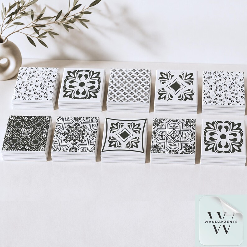 May include: Ten stacks of square ceramic tiles arranged in two rows. Each tile features a distinct black and white pattern, including floral, geometric, and ornate motifs. The tiles are smooth with a glossy finish, showcasing a variety of intricate designs.