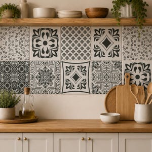 May include: A kitchen backsplash featuring a grid of square tiles with various black and white geometric and floral patterns. The setup includes a wooden countertop, a glass oil cruet, a potted plant, wooden cutting boards, and wooden spoons.