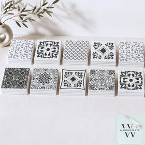 May include: A collection of ten square tiles arranged in two rows, each featuring a distinct black and white graphic pattern. The designs include floral motifs, geometric shapes, and intricate scrollwork. A small logo in the corner reads WANDAKZENTE VV.