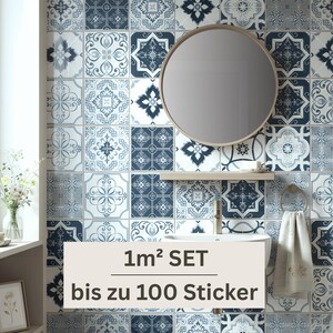 May include: A set of square wall stickers featuring a variety of blue and white geometric and floral patterns. The stickers are applied to a bathroom wall behind a round mirror, a small shelf, a sink faucet, and a hanging white towel.