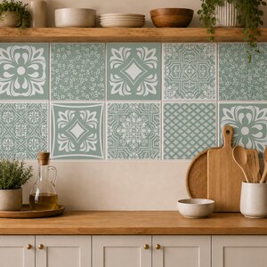 May include: A kitchen backsplash featuring a grid of square tiles in sage green and white. The tiles display a variety of patterns, including floral motifs, geometric shapes, and intricate scrollwork, creating a cohesive decorative wall surface.