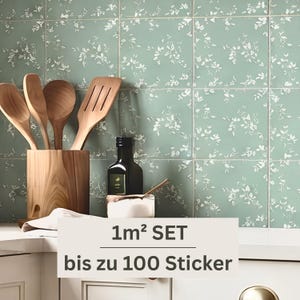 Könnte beinhalten: Ein Set quadratischer Wandaufkleber mit hellgrünem Hintergrund und weißem Blattmuster. Der Text 1m² SET bis zu 100 Sticker ist auf der Vorderseite aufgedruckt. Die Aufkleber sind an einer Küchenwand hinter hölzernen Küchenutensilien angebracht.