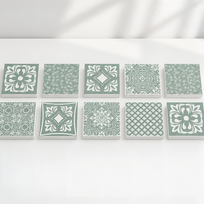 May include: A collection of ten square tiles arranged in two rows of five. Each tile features a sage green background with white printed patterns, including floral motifs, geometric shapes, intricate scrollwork, and repeating diamond designs.