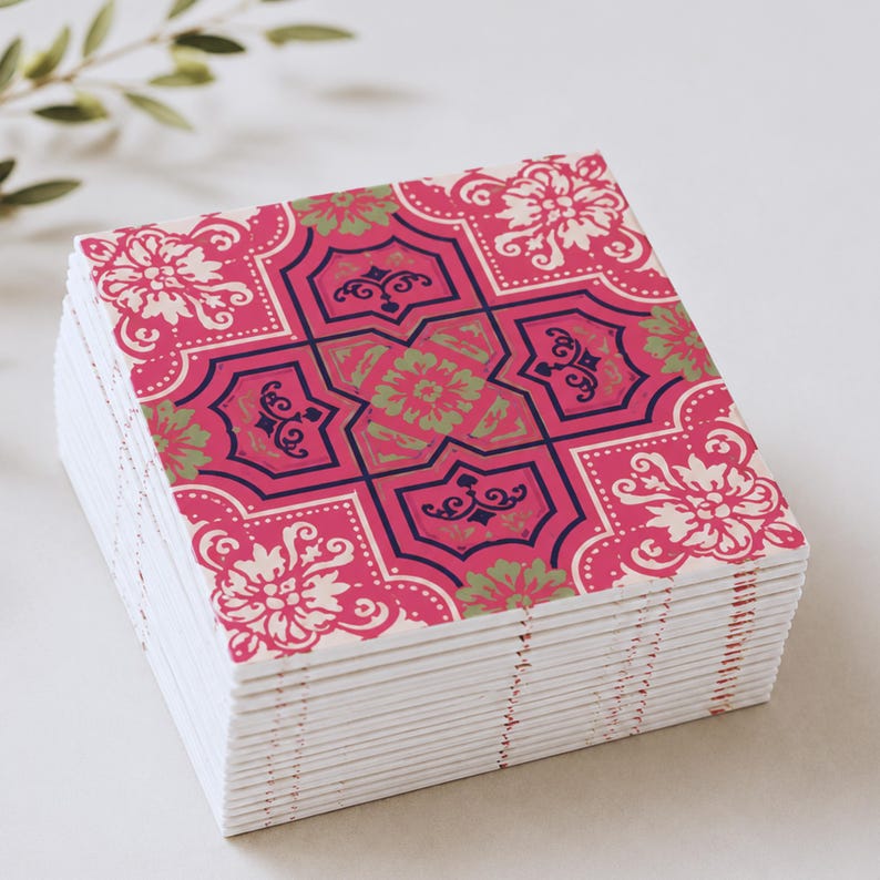 May include: A stack of square coasters featuring a repeating pattern in shades of hot pink, dark navy blue, and pale sage green. The design consists of intricate floral motifs and geometric shapes with white accents on a vibrant pink background.
