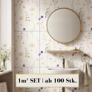May include: A set of square wall tiles featuring a delicate botanical pattern of pale pink flowers, green stems, and small purple blossoms. The tiles are installed in a bathroom with a round mirror, a wooden shelf, and a sink. Text reads 1m² SET | ab 100 Stk.