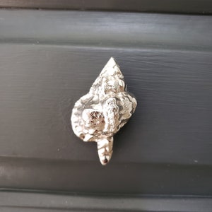 May include: A silver-toned, textured, abstract, leaf-shaped door knob.