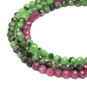 Puede incluir: Una hebra de cuentas de piedras preciosas facetadas verdes y rosas. Las cuentas son redondas y tienen un acabado liso y pulido.