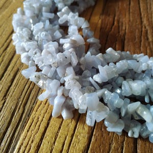 May include: A strand of light blue and white chip gemstone beads. The beads are irregular in shape and have a natural, polished finish.