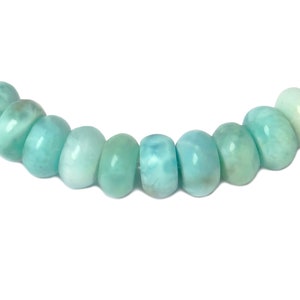 May include: A strand of light blue gemstone beads. The beads are round and have a smooth, polished finish.