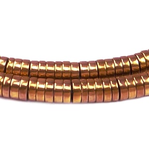 May include: A strand of copper-toned hematite beads, each bead is a flat, round disc with a slightly raised edge. The beads are strung together in a continuous line, creating a smooth, flowing look.