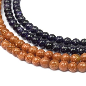 May include: Two strands of brown gemstone beads and one strand of blue gemstone beads. The beads are round and have a speckled appearance.