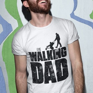 Könnte beinhalten: Weißes T-Shirt mit einem schwarzen grafischen Aufdruck, auf dem "The Walking Dad" mit der Silhouette einer Person steht, die einen Kinderwagen schiebt.