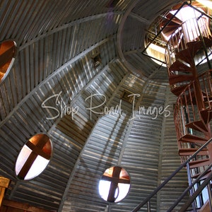 May include: Interior view of a domed ceiling with a spiral staircase. The ceiling is constructed of corrugated metal with oval windows. A red spiral staircase ascends towards a circular opening at the top.