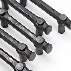 May include: Six black metal cabinet pulls with a hammered finish. Each pull has a round knob on the end.
