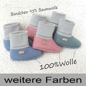 Könnte beinhalten: Drei Paar Babyschuhe in Blau, Rosa und Türkis. Die Schuhe sind aus weichem, flauschigem Stoff und haben einen grauen Umschlag. Der Text "Bündchen 95% Baumwolle" ist oben im Bild sichtbar. Der Text "100% Wolle" ist unten in der Mitte des Bildes sichtbar. Der Text "weitere Farben" ist unten im Bild sichtbar.