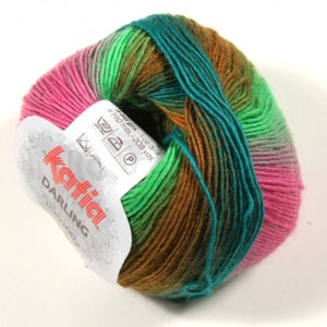 Puede incluir: Un ovillo de hilo Katia Darling en un degradado multicolor de rosa, verde, marrón y turquesa. La etiqueta dice "Katia Darling" e incluye el peso, el metraje y las instrucciones de cuidado.